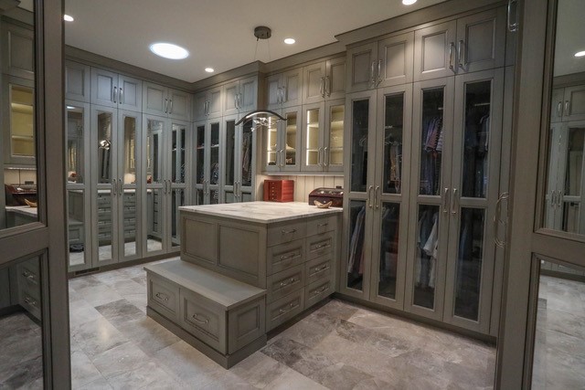 Custom dressing room with glass-front wardrobes and island