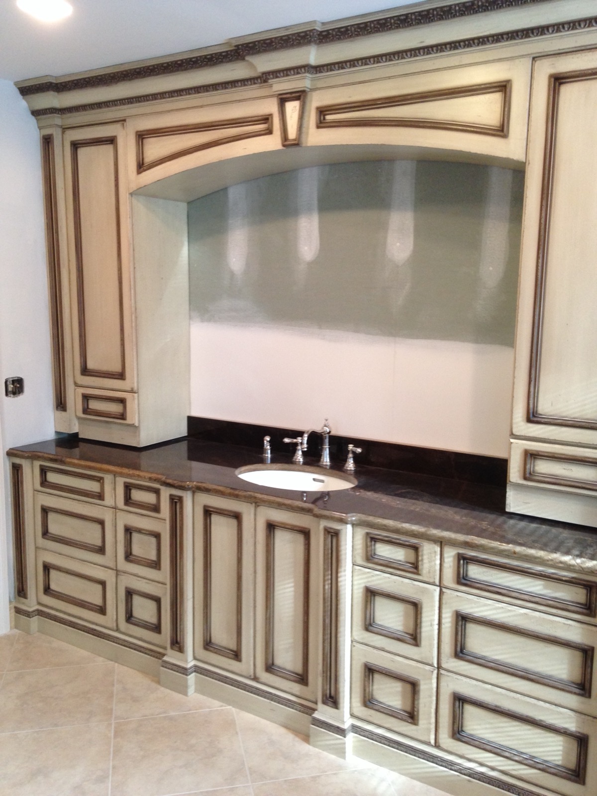 Ornate glazed custom vanity mid-installation, showing hand-detailed carving
