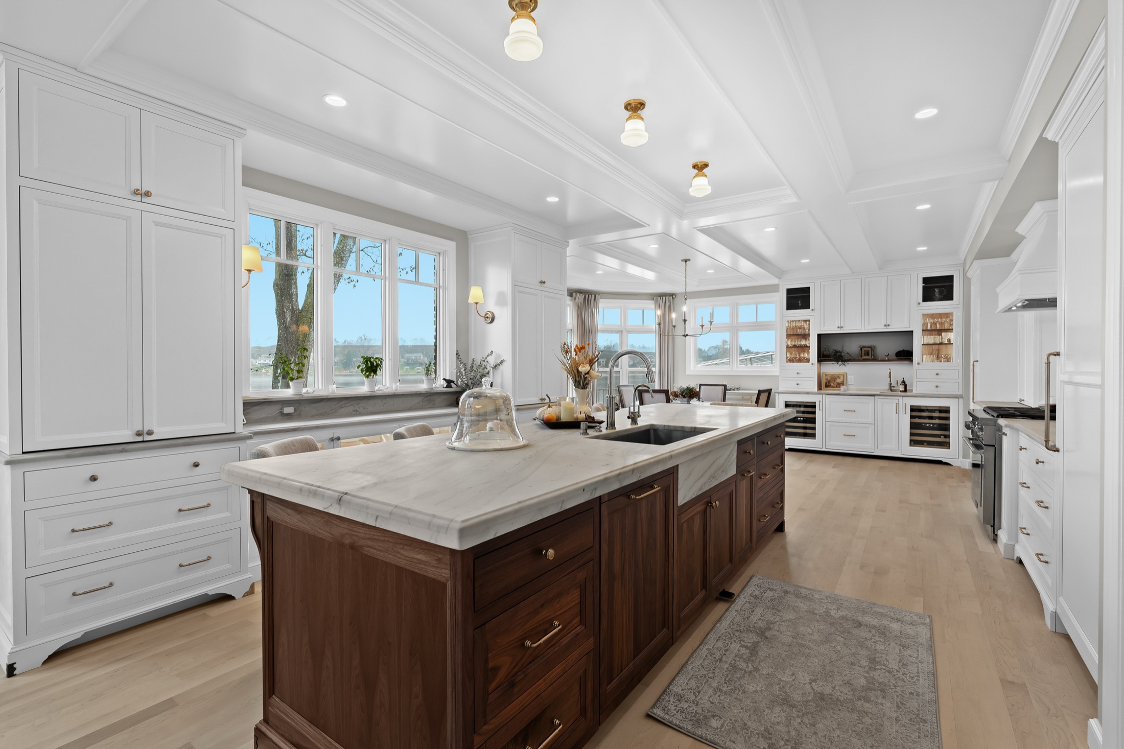 White lakeside kitchen with walnut island and coffered ceiling