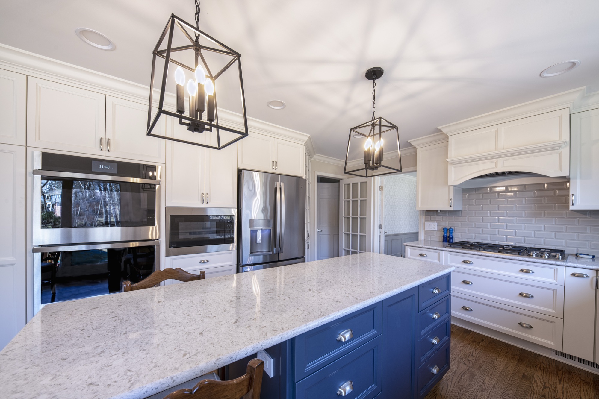 White kitchen with navy island and lantern pendants